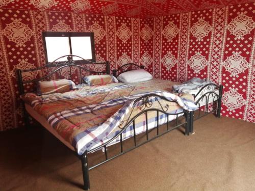 two beds in a room with red wallpaper at Bedouins life camp in Aqaba