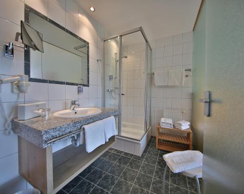 ein Badezimmer mit einem Waschbecken, einem Spiegel und einer Badewanne in der Unterkunft Hotel Pension Geiger in Serfaus