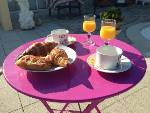 une table rose avec des assiettes de pâtisseries et des verres de jus d'orange dans l'établissement Ajaccio centre ville cosy et spacieux avec climatisation, grande terrasse et vue mer, à Ajaccio