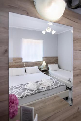two beds in a room with a mirror at Aggelos Apartments & Deluxe Studios in Nydri