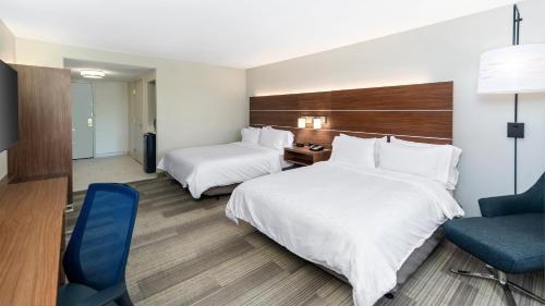 a hotel room with two beds and a blue chair at Holiday Inn Express & Suites Dinuba West by IHG in Dinuba