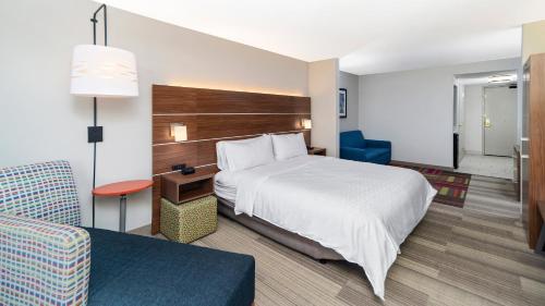 a hotel room with a bed and a chair at Holiday Inn Express & Suites Dinuba West by IHG in Dinuba