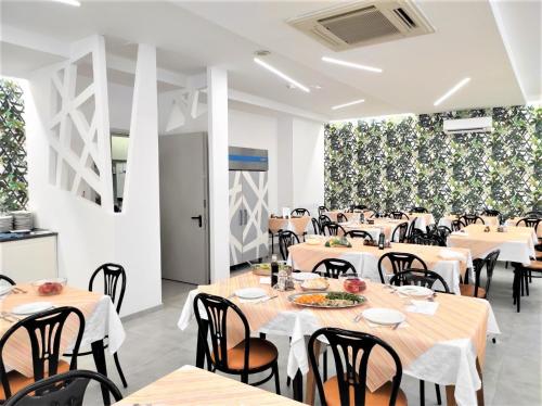 里米尼的住宿－馬德里酒店，用餐室设有桌椅和白色墙壁