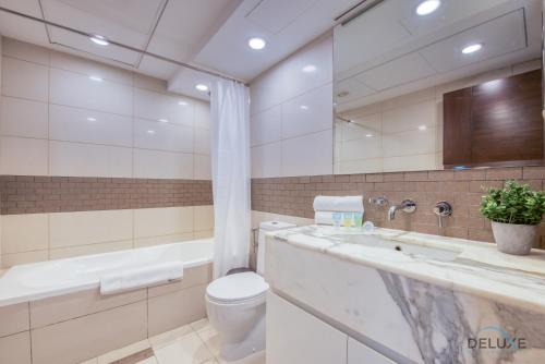 a bathroom with a toilet and a tub and a sink at Airy 1BR at Park Island Sanibel Dubai Marina by Deluxe Holiday Homes in Dubai