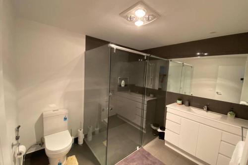 a bathroom with a toilet and a glass shower at Spacious, Contemporary and Self-Contained with Beautiful Views in Kingston