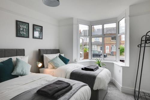 a bedroom with two beds and a window at Spacious Three Bed Central Chelmsford House - Free Parking & Wifi in Chelmsford