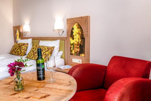 a room with a table with a bottle of wine and a chair at Akzent Waldhotel Rheingau in Geisenheim
