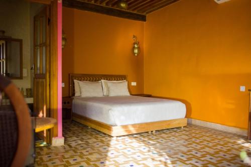 a bedroom with a bed with an orange wall at Medina social club in Fès