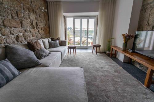 a living room with a couch and a stone wall at Stay In Apartments - D. Hugo 23 in Porto