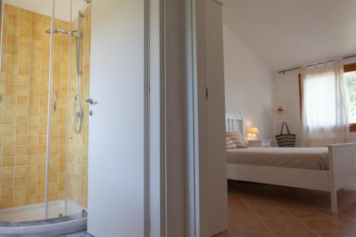 a bathroom with a shower and a bed in a room at DomoMea - Villetta Chia in Domus de Maria