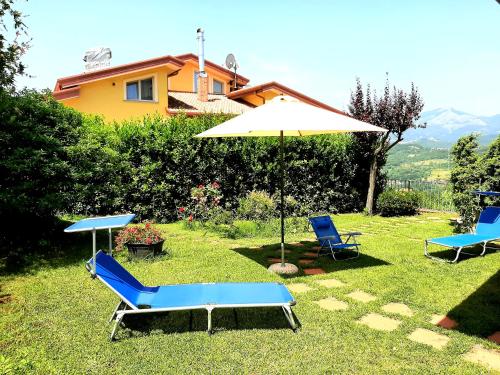 two chairs and an umbrella in the grass at La quercia di Massena in Lauria