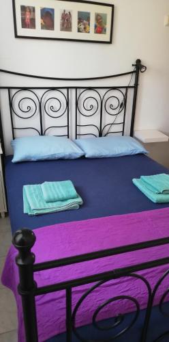 a bed with purple and blue sheets and blue pillows at Olgas Villa in Aroyí