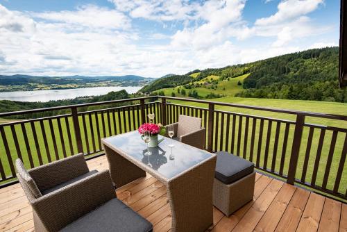a table with chairs and a vase of flowers on a balcony at Ferienwohnungen Schöbringer in Weyregg