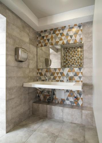 ein Badezimmer mit Waschbecken und gefliester Wand in der Unterkunft REEF Hotel in Koblewe