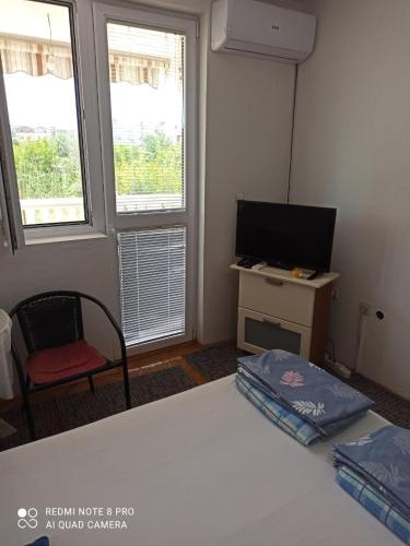 a bedroom with a bed and a tv and two windows at Anika apart in Bar