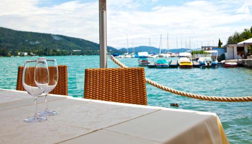 a wine glass sitting on a table next to the water at Hotel-Restaurant "Veldener Traumschiff" direkt am See in 2min im Zentrum in Velden am Wörthersee