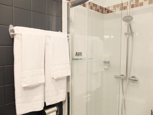 a bathroom with white towels and a shower at Aux Temps d'Em in Montreuil-sur-Mer