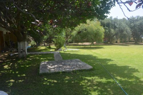 a park with a tree and a bench in the grass at Filoxenia Apartments in Riza