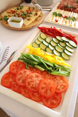 a white plate with tomatoes and vegetables on a table at Hotel Murter in Murter