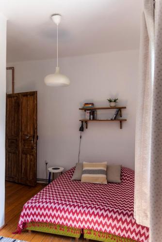 a bedroom with a bed with a red and white blanket at Liget Vendégház in Révfülöp