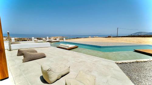 a patio with chairs and a swimming pool next to the beach at Aeris suites Pori in Koufonisia