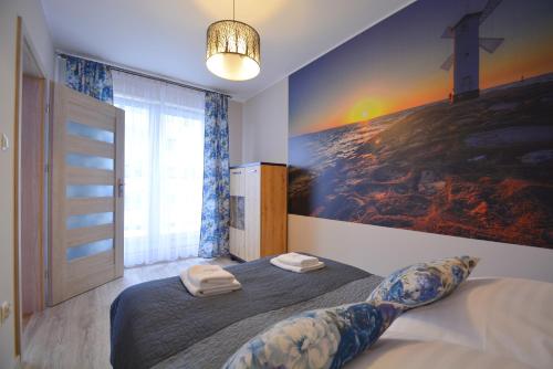 a bedroom with a large bed with a painting on the wall at Apartamenty Bryza-Monte Cassino 8 in Świnoujście