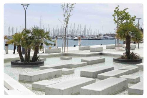 a park with white benches and palm trees near the water at Luxury apartment Eni on the West Coast in Split