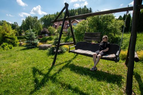 a woman sitting on a swing in a yard at DOMKI - Kaszuby Resort ZACISZE - new cottage in Chmielno