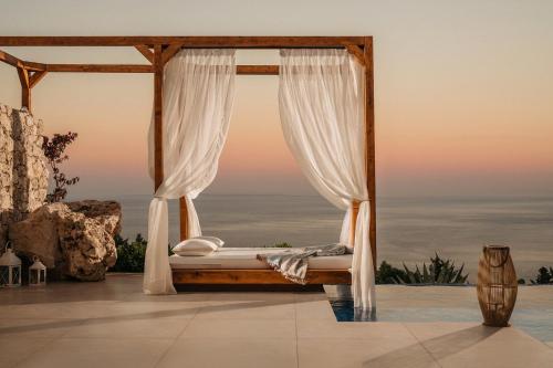 a bed in a room with a view of the ocean at Emerald Villas & Suites - The Finest Hotels Of The World in Agios Nikolaos