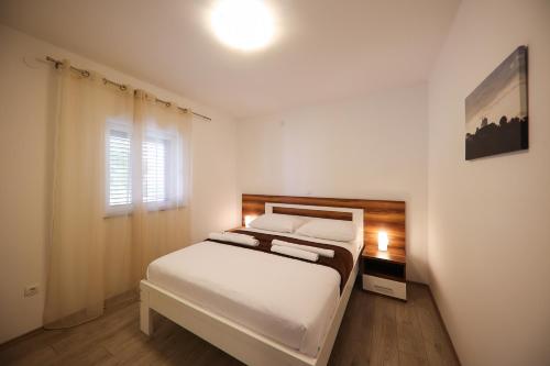 a white bedroom with a bed and a window at Hotel Murter in Murter