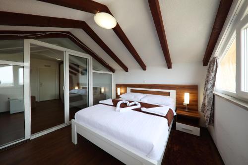 a bedroom with a large white bed and a mirror at Hotel Murter in Murter