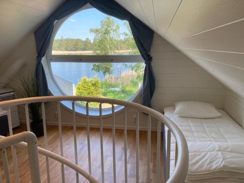um quarto com uma cama e uma grande janela em Brygghuset, Solviken em Rockneby