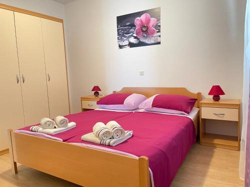 a bedroom with a bed with pink sheets and towels at Apartments Lores in Rab