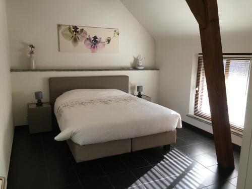 een slaapkamer met een wit bed en 2 ramen bij Hof van Eggertingen nr. 8 in Riemst