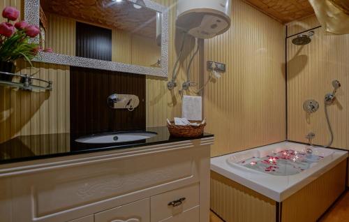 a bathroom with a tub and a sink and a mirror at WelcomHeritage Gurkha Houseboats in Srīnagar