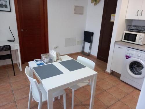 a white table and chairs in a kitchen with a washing machine at APARTAMENTO MOCHIMA in Cotillo