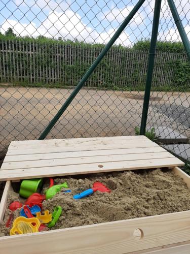 a wooden sandbox with toys in the sand at Apartmán Studnice in Nové Město na Moravě