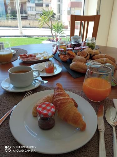un tavolo con colazione a base di cornetti, caffè e succo d'arancia di Pedrógão Guesthouse a Pedrógão