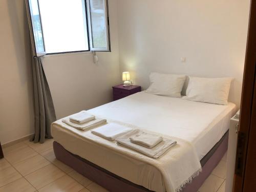 sypialnia z łóżkiem z białą pościelą i oknem w obiekcie Menelaos Apartments w Adelianos Kampos