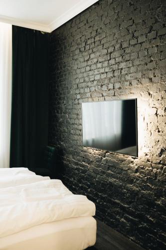 a bedroom with a tv on a brick wall at RATUSZOVA Stary Rynek Old Market PREMIUM Apartments & Restaurant AD 1954 in Poznań