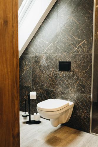 a bathroom with a toilet and a black wall at RATUSZOVA Stary Rynek Old Market PREMIUM Apartments & Restaurant AD 1954 in Poznań