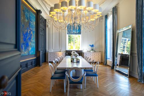 uma sala de jantar com uma mesa e cadeiras e um lustre em Les Garennes - Hôtel Spa Bénodet em Bénodet