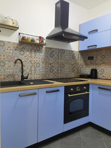 a kitchen with blue cabinets and a black oven at Apartment PEK in Crikvenica