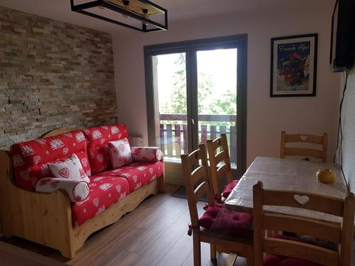 a living room with a red couch and a table at Appartement Saint Gervais les Bains vue imprenable Mont Blanc in Saint-Gervais-les-Bains