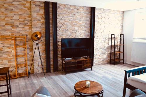 a living room with a television and a brick wall at Schönes und barrierefreies Loft in Kreuzau in Kreuzau