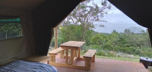 a room with a table and benches on a porch at Trees&Seas - Glamping with farm animals in Wilderness