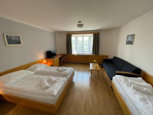 a hotel room with two beds and a couch at Hotel Laguna & restaurant in České Budějovice