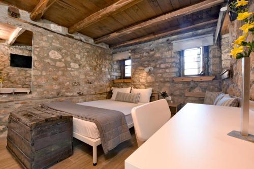 1 dormitorio con cama y pared de piedra en Casa La Bohema, en Afitos