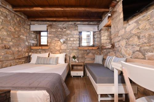 a bedroom with two beds and a bench in a stone wall at Casa La Bohema in Afitos