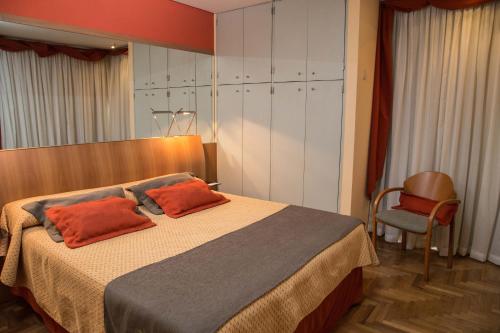 a bedroom with a bed with two orange pillows on it at King David Flat Hotel - Argentina in Córdoba